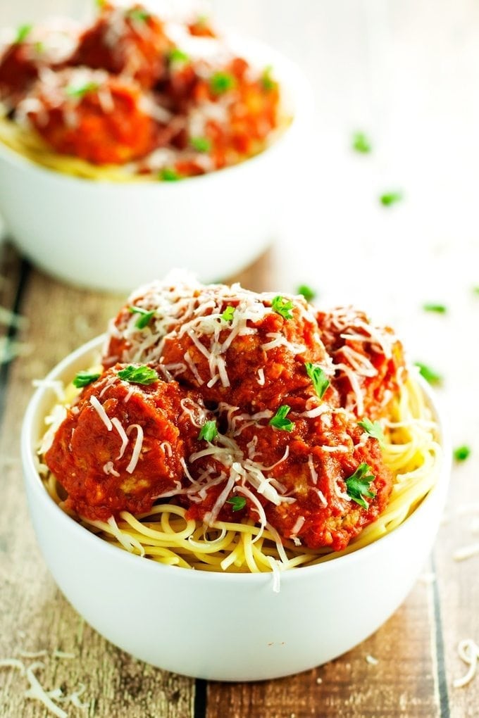 Two heaping bowls of baked turkey meatballs served over spaghetti for an easy, complete dinner.