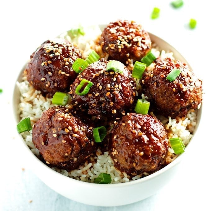 beef teriyaki meatballs served over rice and topped with sesame seeds and green onions