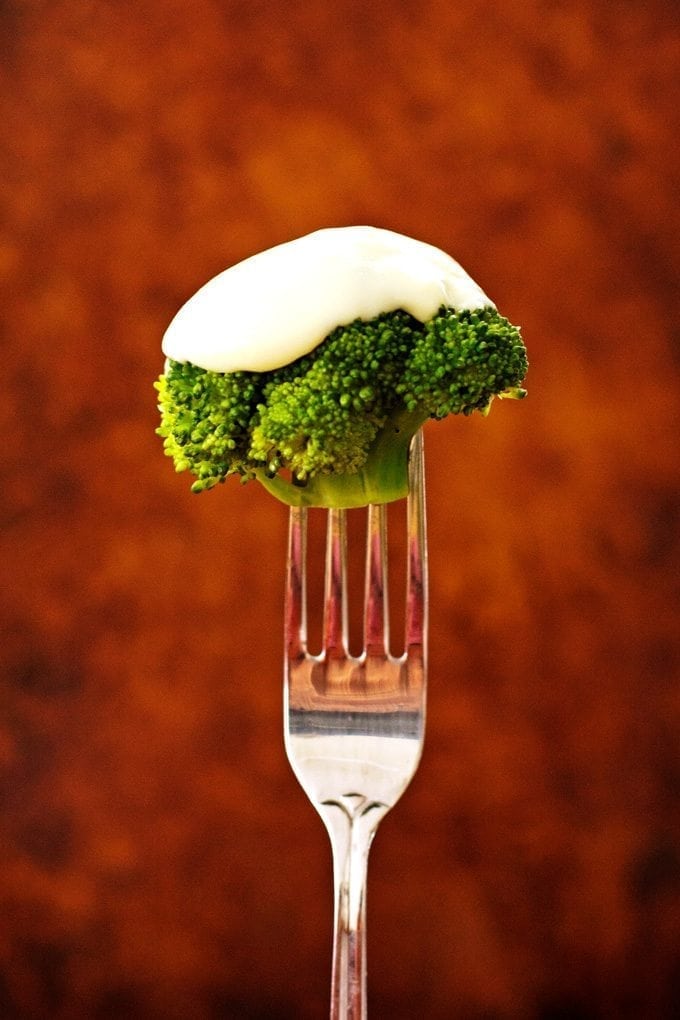 Broccoli covered in cheese sauce on a fork