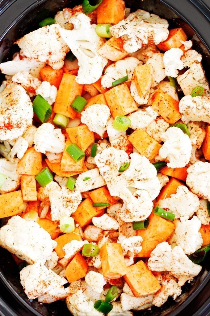 crockpot slow cooker full of cauliflower florets, cubed sweet potatoes, and chopped green onions