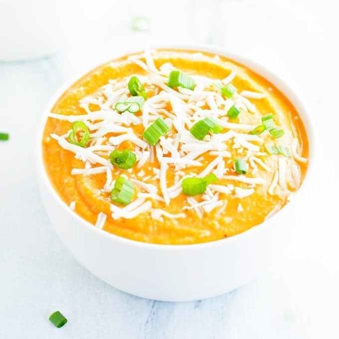 creamy bowl of cauliflower sweet potato soup topped with green onions and shredded cheese