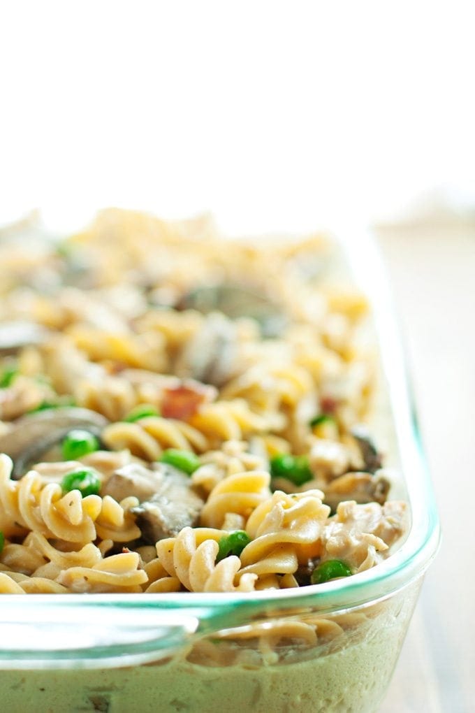 baking dish full of chicken tetrazzini before being topped with breadcrumbs. Here you can see the pasta, chicken, mushrooms, peas, and bacon.