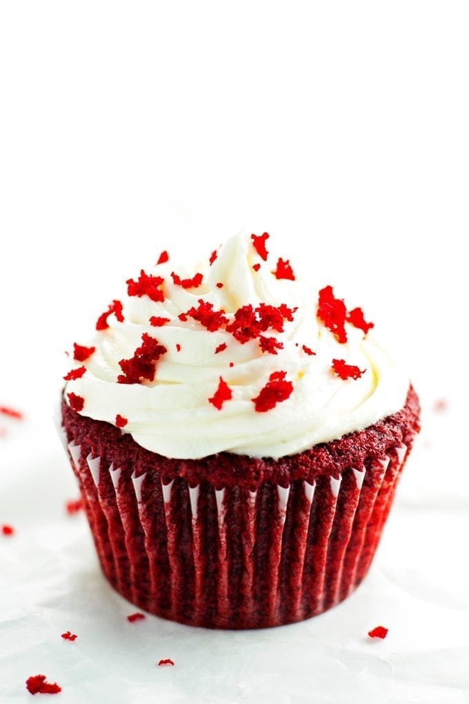 single red velvet cupcake topped with cream cheese frosting and cupcake crumbs